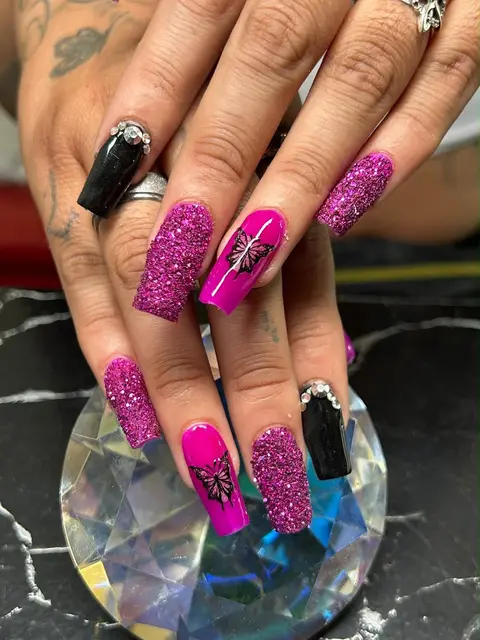 Uñas fucsia con glitter y diseño de mariposa