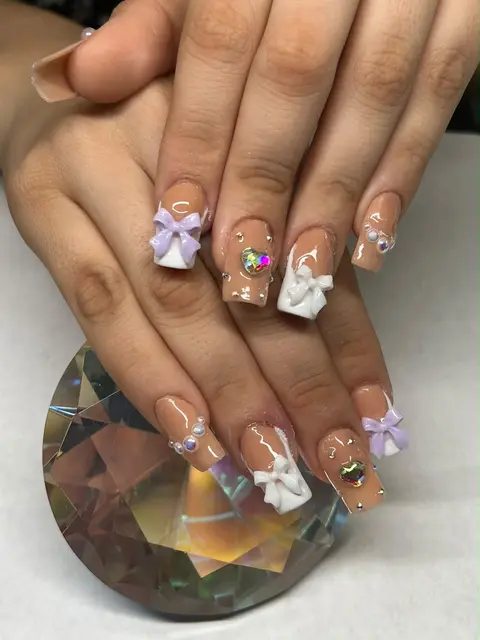 Uñas nude con moños en relieve y pedrería
