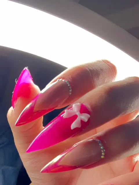 Uñas stiletto rosa fucsia con moño y brillos